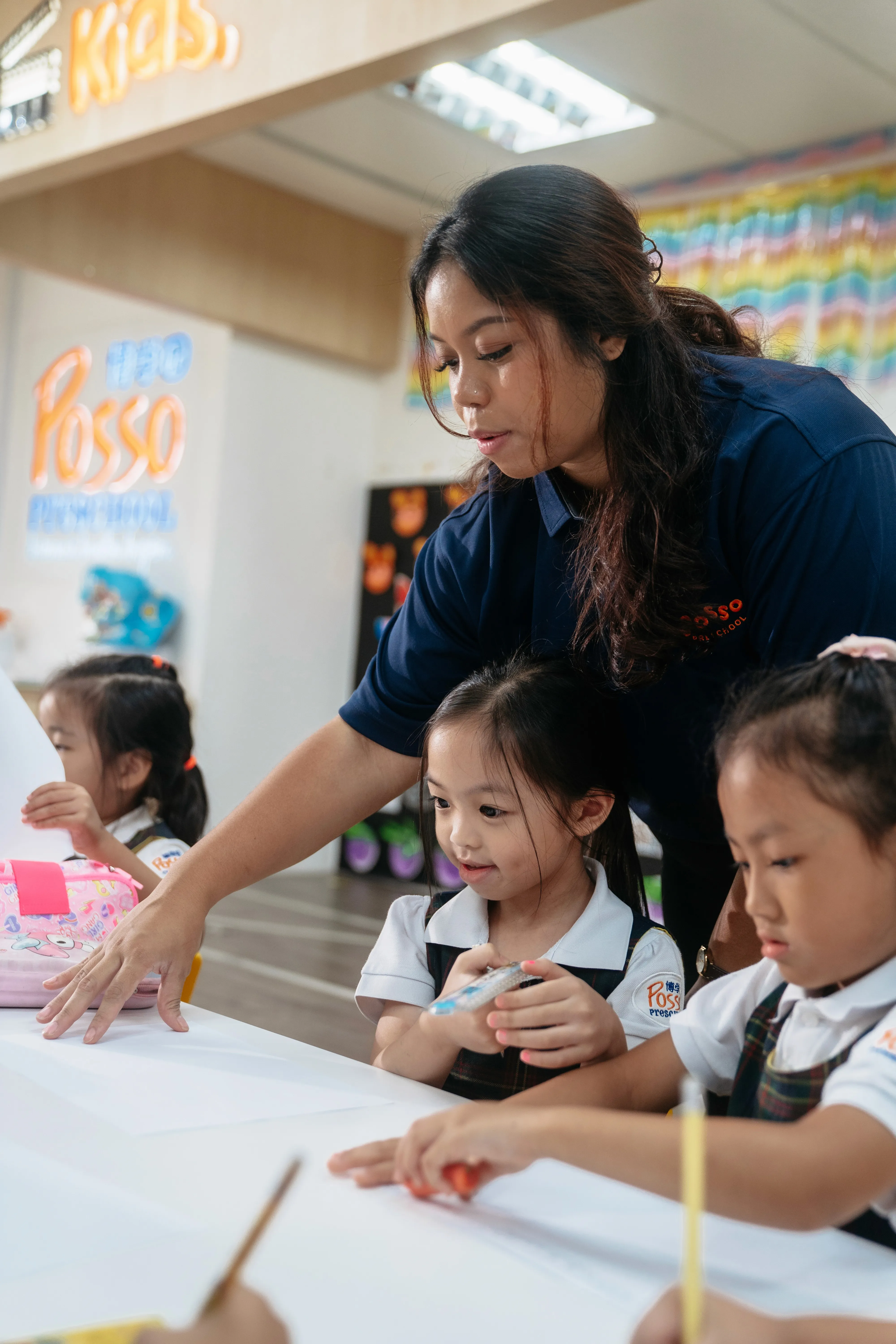Teacher guiding children at a table
