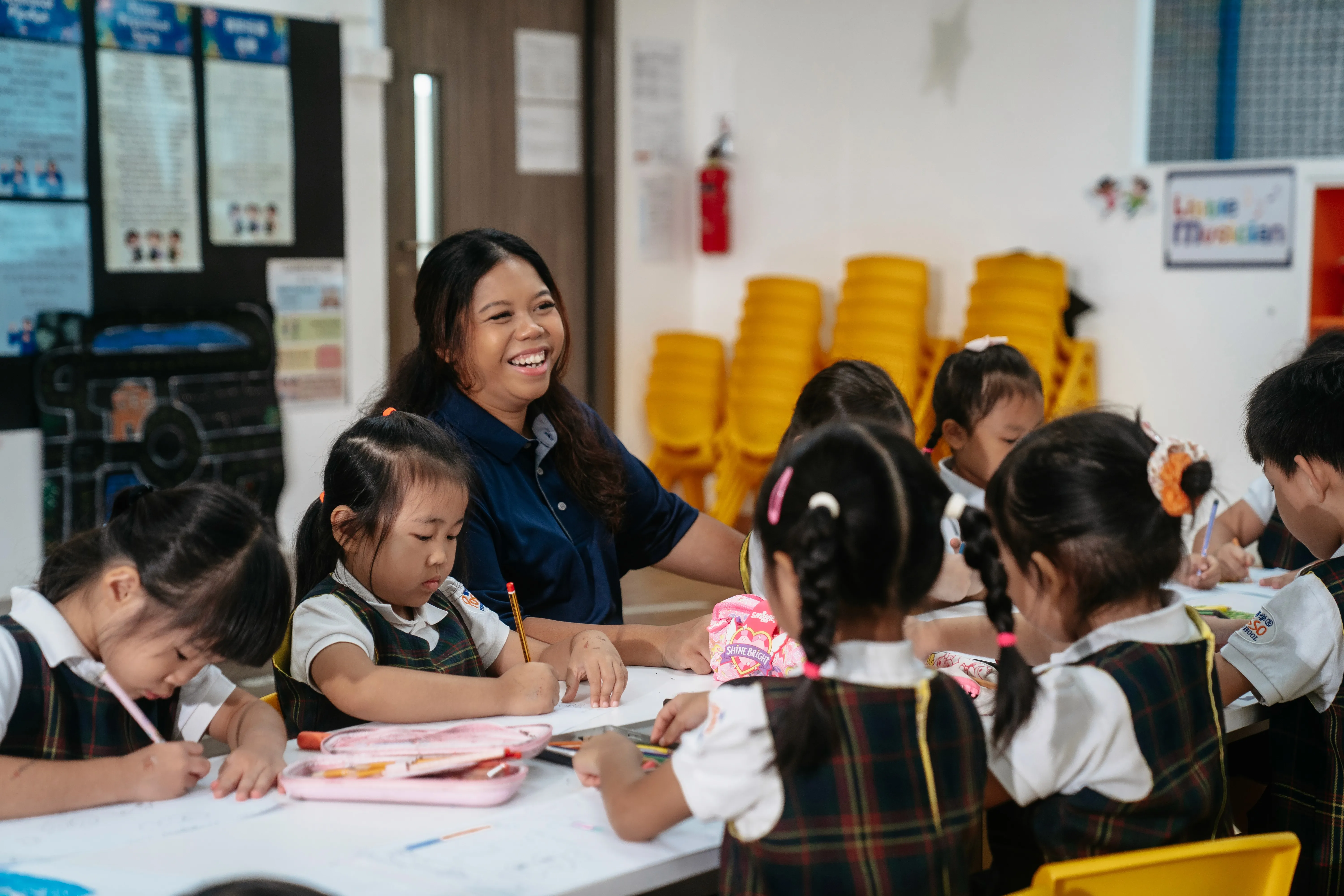 A Posso teacher smiling with children at their desks
